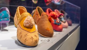 Photo of a line of five brightly colored slippers in a museum case