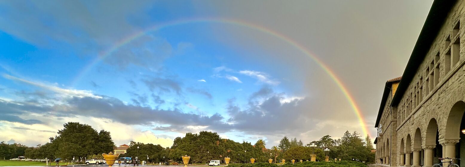 Photo of a rainbow stretching across Jane Stanford Way at the entrance to Stanford University
