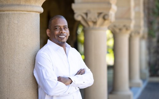 A. Van Jordan wearing a white button-down shirt and leaning against one of the columns of Stanford University's Main Quad