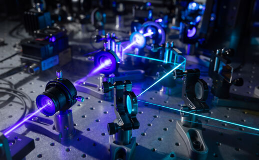 closeup of part of the iISM microscope showing a purple laser moving through several lenses 