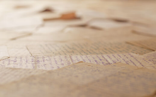 Table covered with many old letters. Angle view, selective focus. Text is unrecognizable.