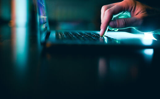 Fingers on the track pad of a laptop in a dark room