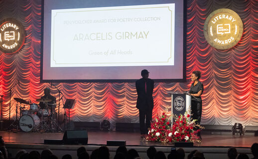 Aracelis Girmay stands a lectern on a stage