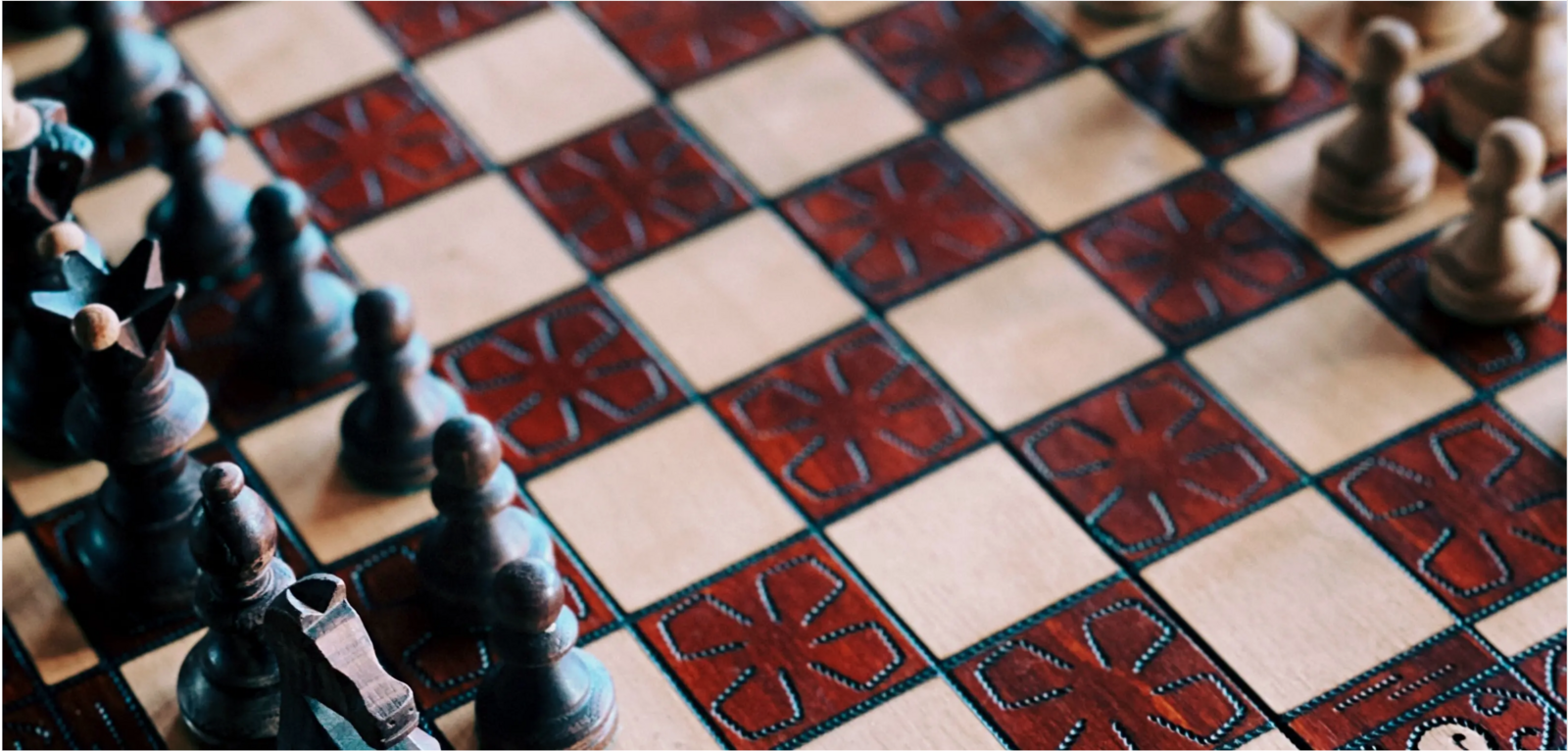 A close-up photo of chessboard with alternating red and white squares and black and white chess pieces