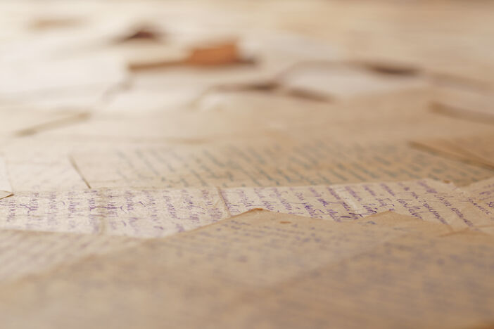 Table covered with many old letters. Angle view, selective focus. Text is unrecognizable.