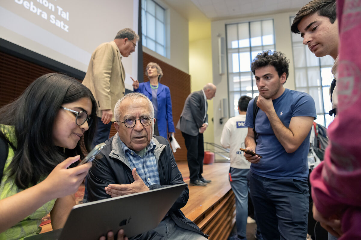 A group of students talk with Salam Fayyad while Larry Diamond and Debra Satz talk in the background