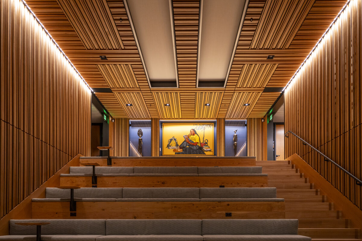 Wooden stadium seating leads up to painting covered by a wood-slat ceiling