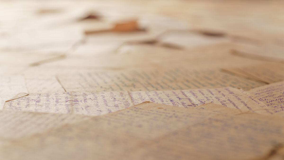 Table covered with many old letters. Angle view, selective focus. Text is unrecognizable.
