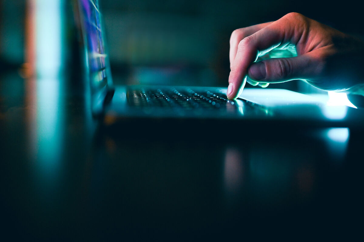 Fingers on the track pad of a laptop in a dark room