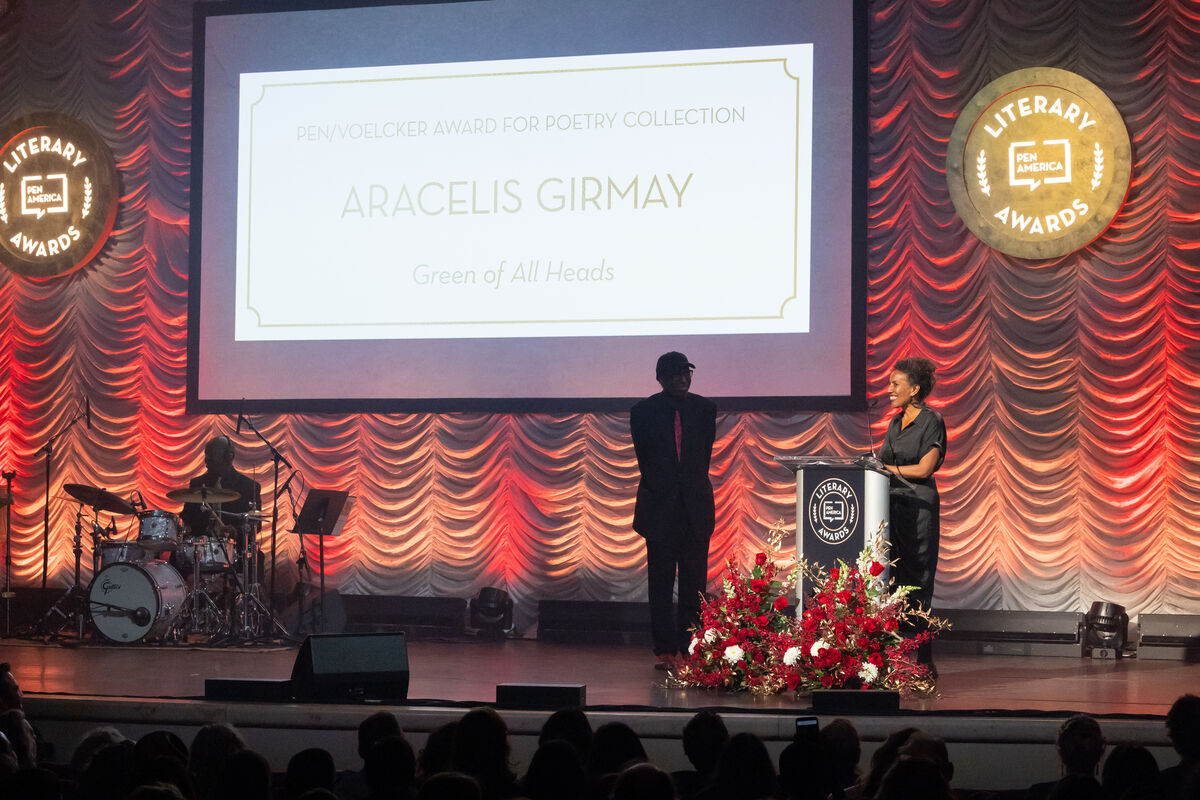 Aracelis Girmay stands a lectern on a stage