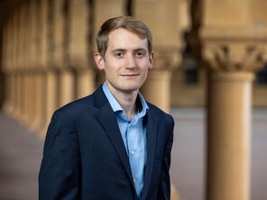 Photo of Ben Moran wearing a light-blue collared shirt and a dark-blue jacket