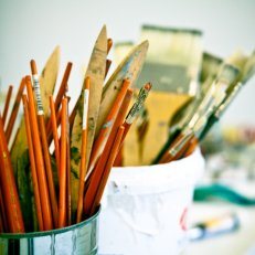 Artist supplies, including brushes and pencils, upright in cups.