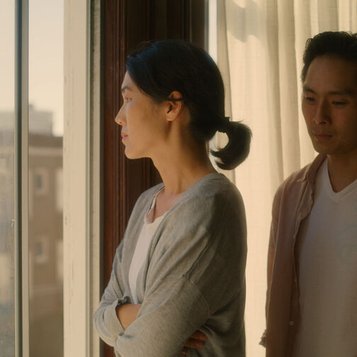 Woman standing in front of man looking away