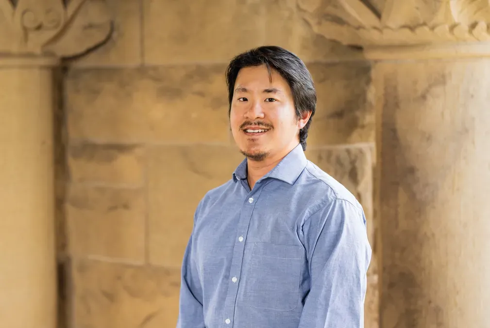 Statistician Dennis Sun stands in front of sandstone pillars and wall