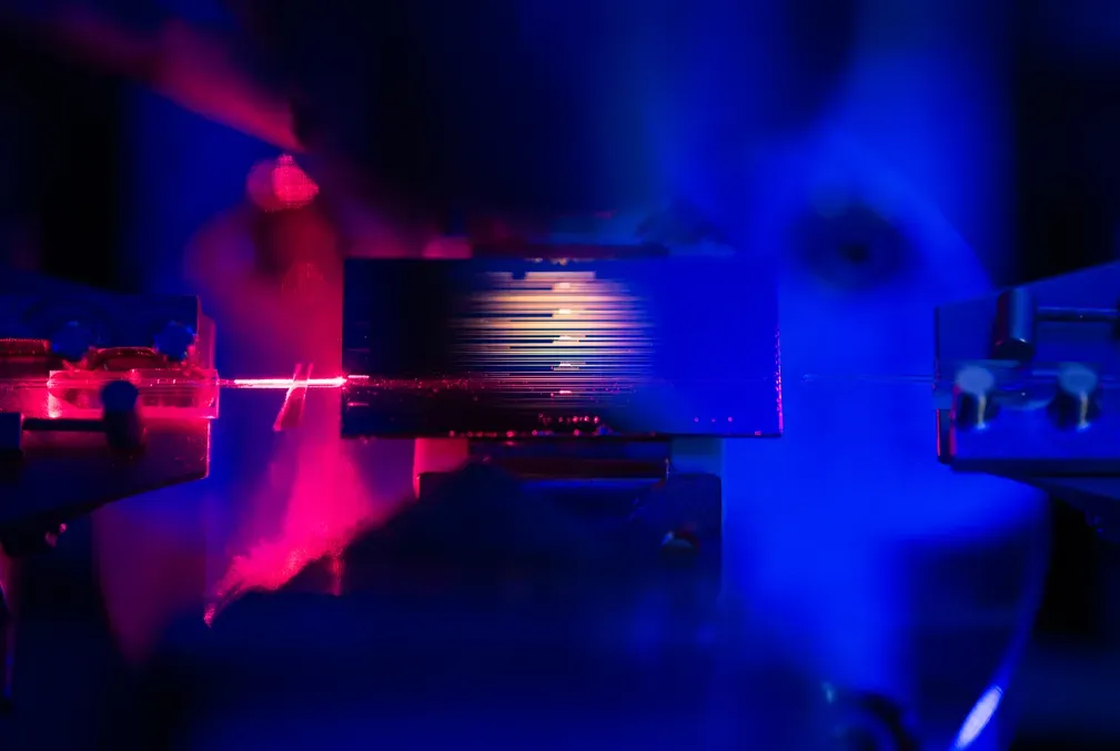 Close up of an optical amplifier chip, similar to the one detailed in the new study, that is being developed in the lab of Stanford physicist Amir Safavi-Naeini. A red laser light shines from an optical fiber on the left to help with aligning the fiber to the chip.