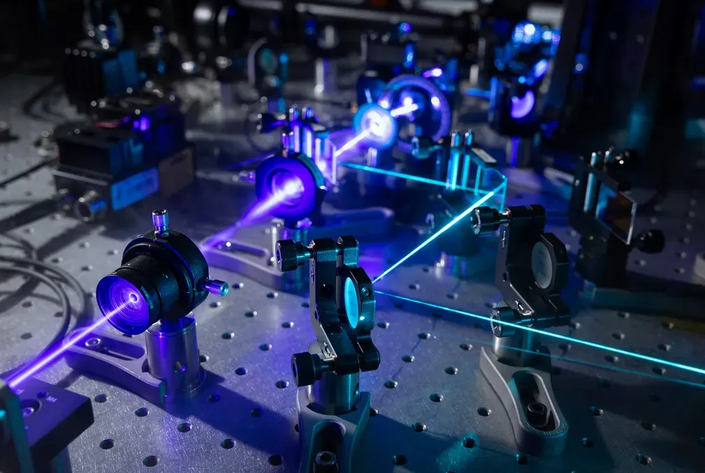 closeup of part of the iISM microscope showing a purple laser moving through several lenses 