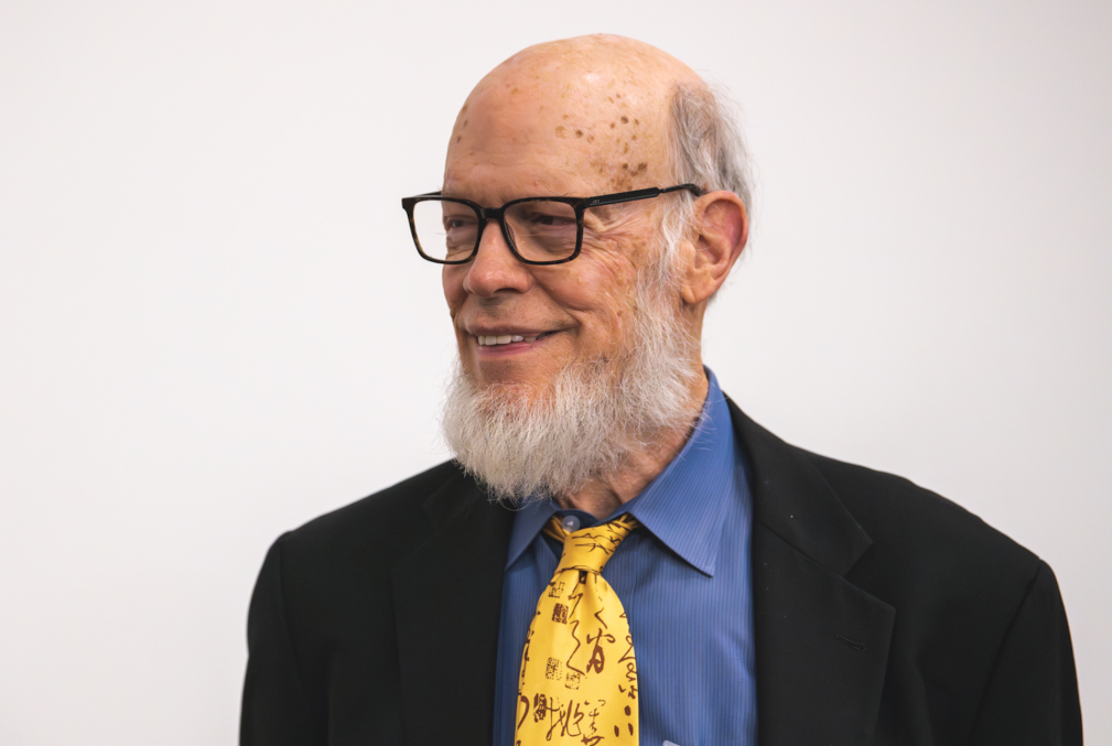 David Siegmund wearing glasses and wearing a black sport coat, blue collared shirt, and a yellow tie