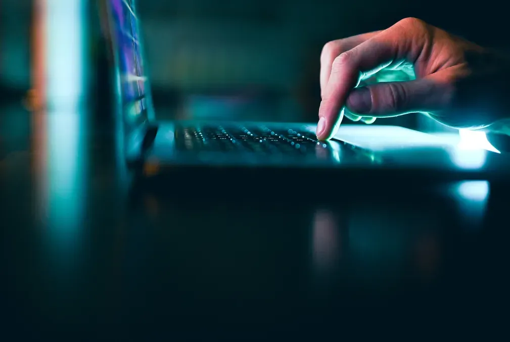 Fingers on the track pad of a laptop in a dark room