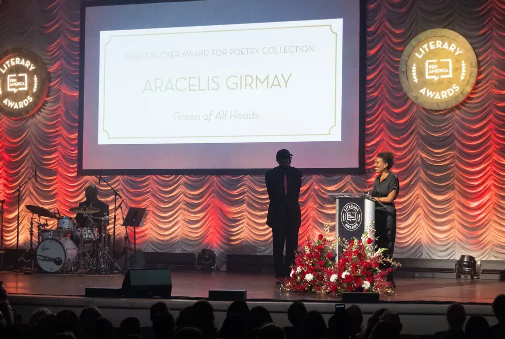 Aracelis Girmay stands a lectern on a stage
