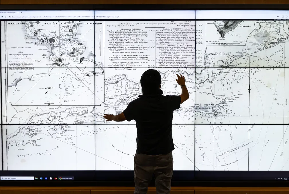 Student stands in front of the interactive screen in the Rumsey Map Center