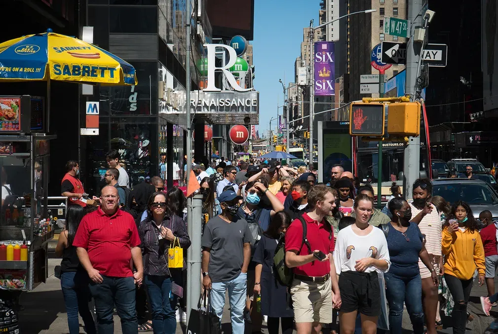 A busy crowd in Times Square, New York, during the height of the COVID-19 pandemic with a varying degree of masking