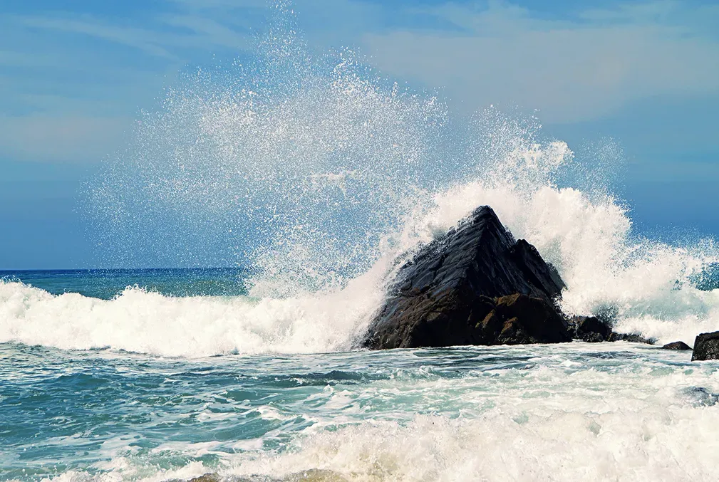 An ocean wave crashes against a rock 